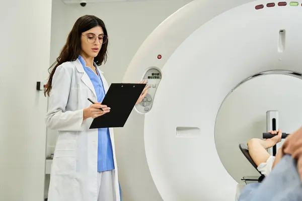 A female doctor in a lab coat stands by an MRI machine, preparing for patient diagnostics. — Stock Photo