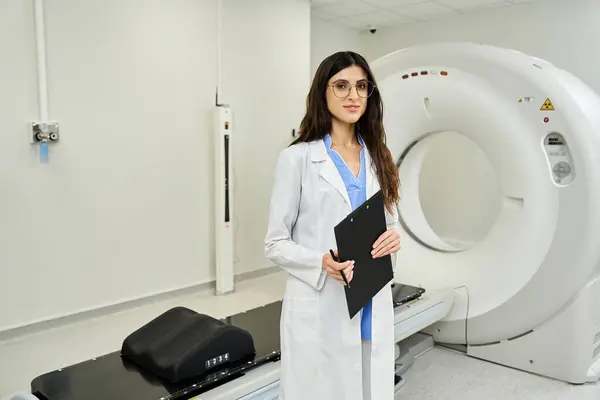 Attractive female doctor stands confidently in a radiology unit, holding a clipboard. — Stock Photo