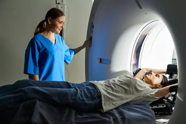 A female doctor in a lab coat attentively guides a patient inside an MRI machine at the hospital. — Stock Photo