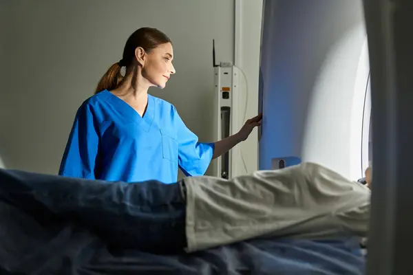 Um médico qualificado em um jaleco verifica um paciente em uma máquina de ressonância magnética para segurança e conforto. — Fotografia de Stock