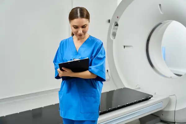 A female doctor in a lab coat reviews patient info at a diagnostic mri machine. — Stock Photo