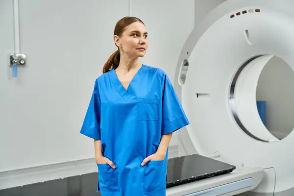 An attractive female doctor stands confidently beside advanced radiology equipment in a hospital. — Foto stock