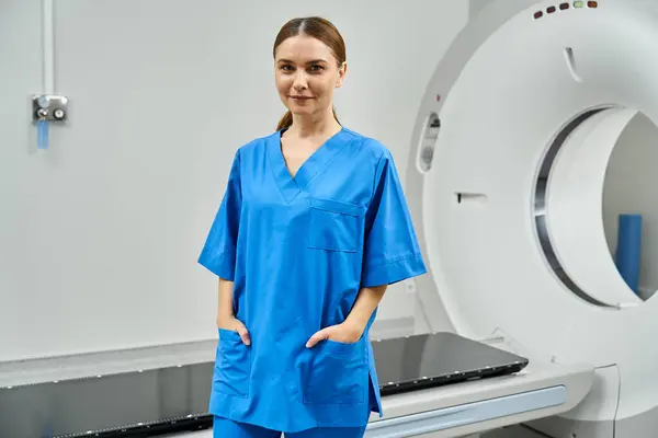 Médica feminina confiante em esfoliação azul fica ao lado de uma máquina de ressonância magnética, pronta para diagnóstico. — Fotografia de Stock