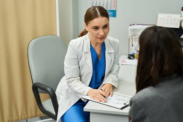 A gynecologist in a lab coat discusses health concerns with a female patient in a clinic. — Stock Photo