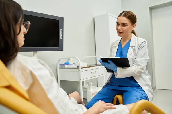 A gynecologist in a lab coat discusses health issues with a female patient during a checkup. — Stock Photo