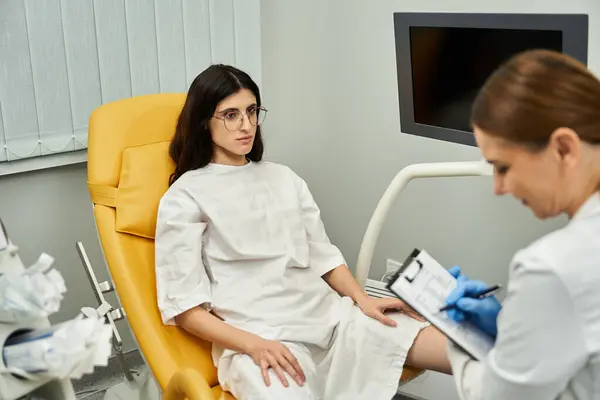 Um ginecologista ajuda uma paciente feminina durante um exame de saúde em um consultório médico moderno. — Fotografia de Stock