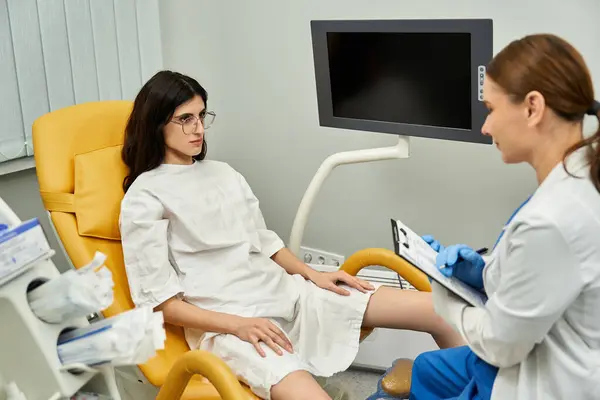 Um ginecologista em um jaleco discute problemas de saúde com uma paciente do sexo feminino em uma clínica. — Fotografia de Stock