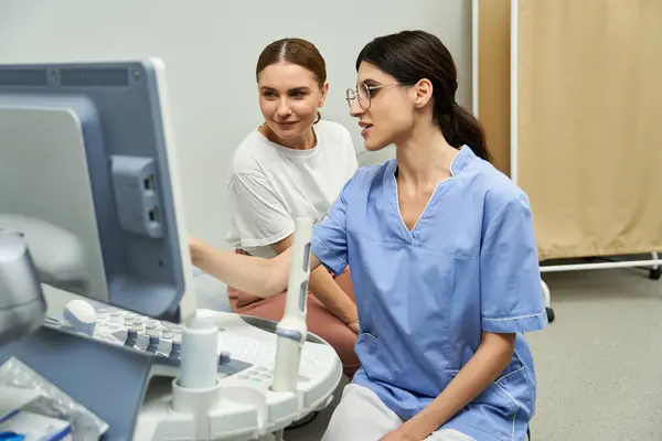 A gynecologist in a lab coat works at a computer, guiding a female patient through diagnostics. — Stock Photo