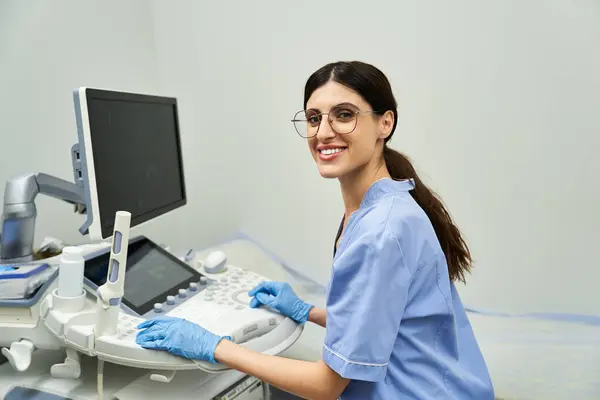 A dedicated gynecologist in a lab coat smiles while using ultrasound equipment. — Stock Photo