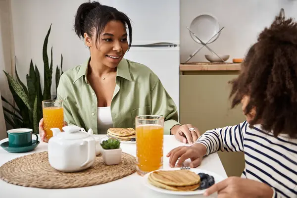 A mother and daughter bond over breakfast while sharing smiles and joy in their cozy kitchen. — Stock Photo