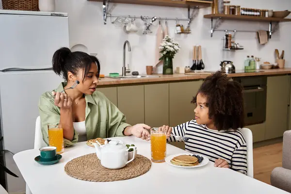 Uma mãe e uma filha compartilham um alegre café da manhã, saboreando panquecas e bebidas juntas.. — Fotografia de Stock