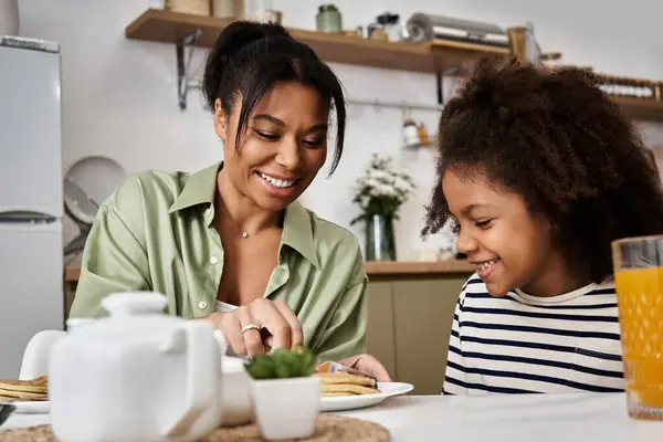 Loving mother prepares breakfast with her cheerful daughter in a cozy kitchen setting — Stock Photo