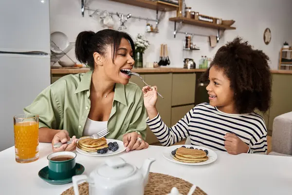 Mother and daughter share a cozy breakfast of pancakes and fresh fruit. — Stock Photo