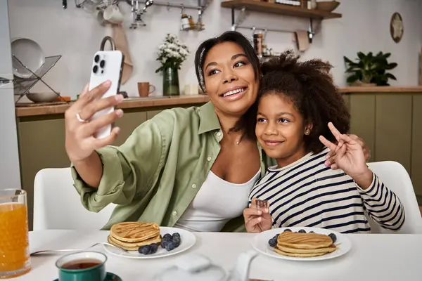 Mother and daughter enjoy breakfast, capturing a perfect moment while sharing smiles and pancakes. — Stock Photo