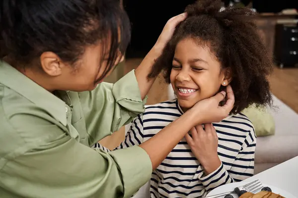 Une mère coiffe joyeusement ses filles de cheveux, montrant leur lien d'amour dans une maison moderne. — Photo de stock