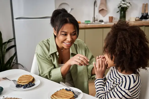 Una madre si diletta nell'interazione giocosa con sua figlia durante un'accogliente colazione insieme.. — Foto stock