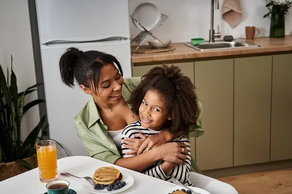 A loving mother shares a warm breakfast with her daughter, filled with laughter and connection. — Stock Photo
