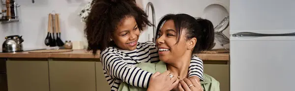 Loving mother embraces her daughter, sharing smiles and laughter in a warm kitchen. — Stock Photo