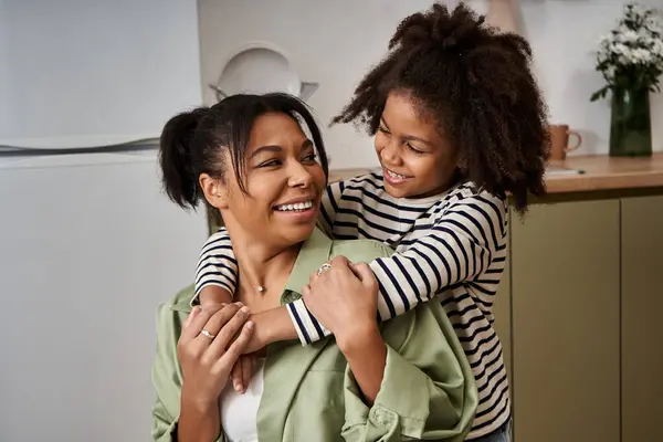 A loving mother shares a joyful embrace with her daughter in a warm kitchen setting. — Stock Photo