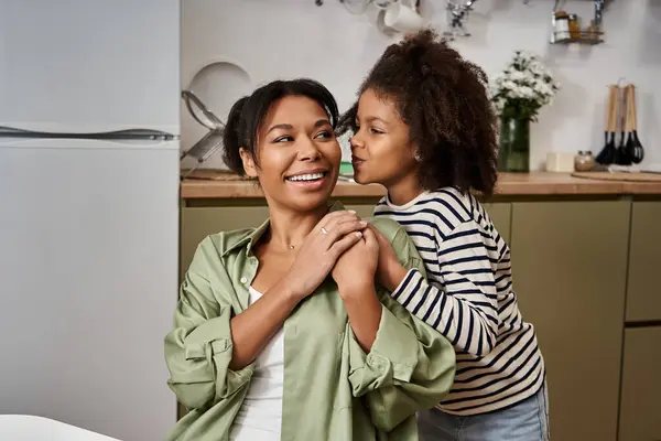 A smiling mother shares a cheerful moment with her daughter while cooking together at home. — Stock Photo