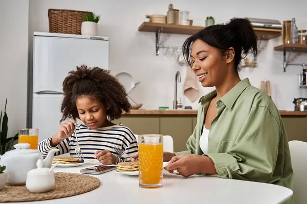 Mère aimante et sa fille profitent d'un délicieux petit déjeuner tout en partageant sourires et crêpes. — Photo de stock