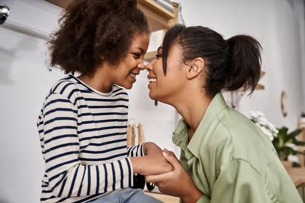 Una madre y su pequeña hija comparten risas alegres en un cálido y nutritivo abrazo. - foto de stock