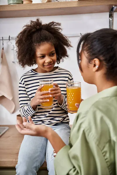 Two family members bond over cold beverages in a cozy kitchen filled with warmth and joy. — Stock Photo
