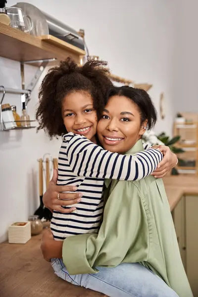 A loving mother shares a heartfelt moment with her daughter in a cozy kitchen setting. — Stock Photo