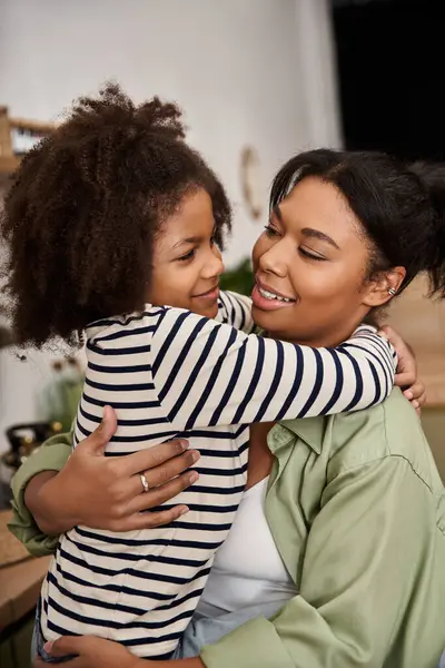 Una madre amorevole abbraccia la sua bambina con calore e gioia in un ambiente domestico accogliente. — Foto stock