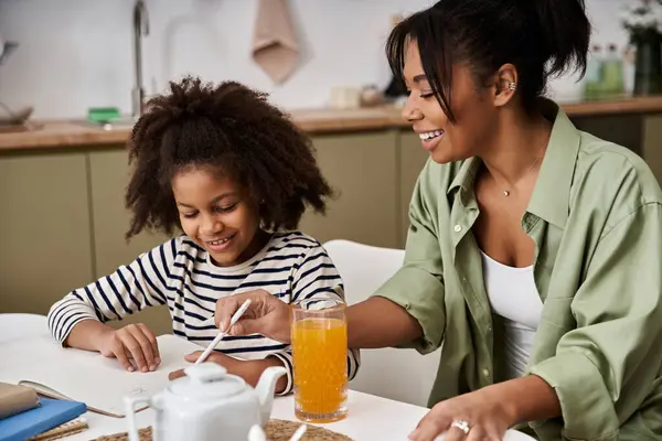 A mother shares laughter and creativity with her young daughter while enjoying a refreshing drink. — Stock Photo