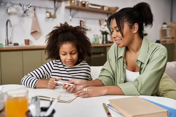 Una madre coinvolge sua figlia nell'apprendimento mentre esplorano insieme al loro accogliente tavolo da cucina. — Foto stock