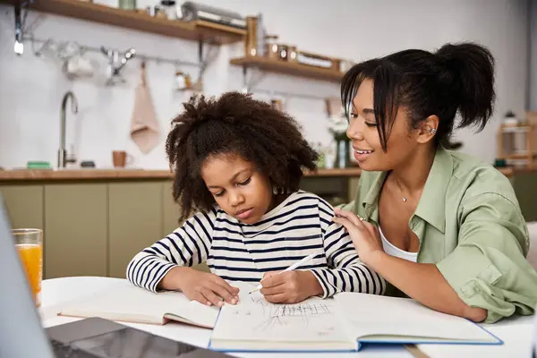 A mother helps her daughter draw and bond in their bright kitchen one afternoon. — Stock Photo