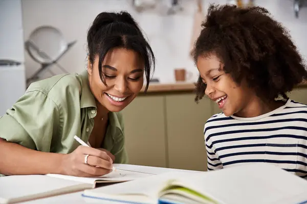 A mother enjoys a playful art moment with her daughter at a cozy kitchen table while drawing. — Stock Photo