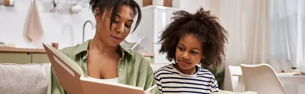 A loving mother shares a delightful story with her daughter in their bright living space. — Stock Photo