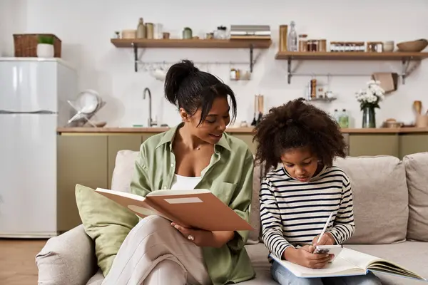 A mother shares a joyful moment with her daughter as they explore books together at home. — Stock Photo
