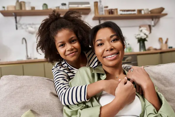 A mother embraces her daughter while enjoying quality time in their cozy living space. — Stock Photo