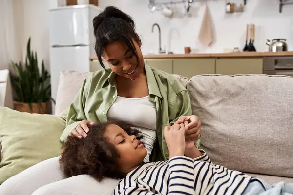 A mother enjoys quality time with her daughter, nurturing warmth in their cozy living room. — Stock Photo