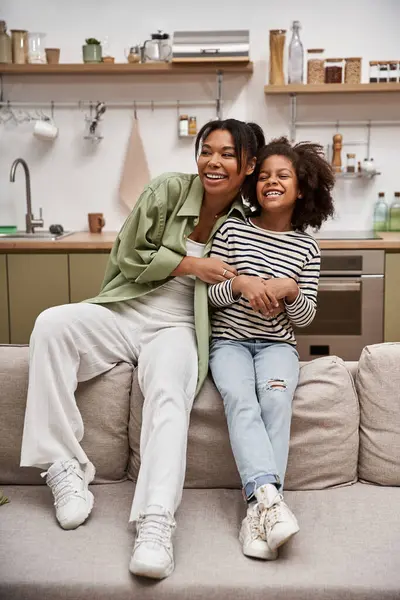 A loving mother and her joyful daughter share laughter in their cozy living room. — Stock Photo