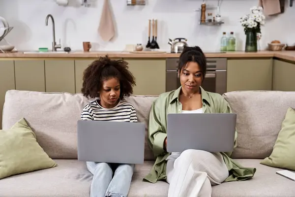 Mother and daughter engage in focused learning while sitting on a cozy couch at home — Stock Photo