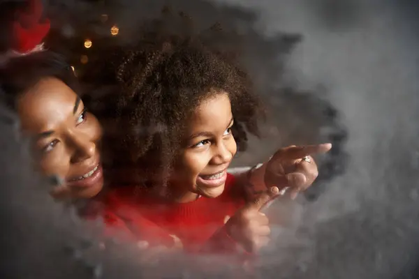 A mother and daughter share a joyful moment, pointing and smiling at the world outside. — Stock Photo