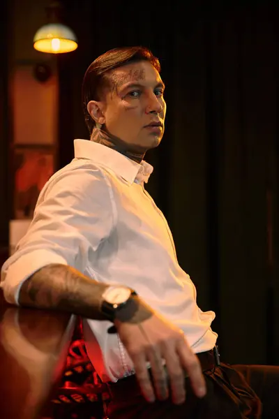 A stylish tattooed young man relaxes in a bar, soaking up the energetic evening atmosphere. — Stock Photo