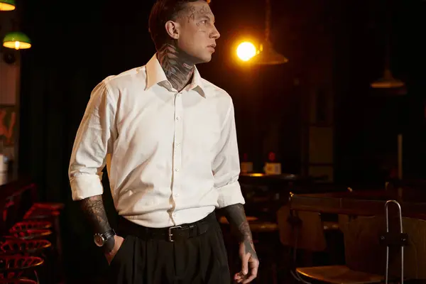 A tattooed young man stands confidently in a lively bar, soaking in the nightlife atmosphere. — Stock Photo
