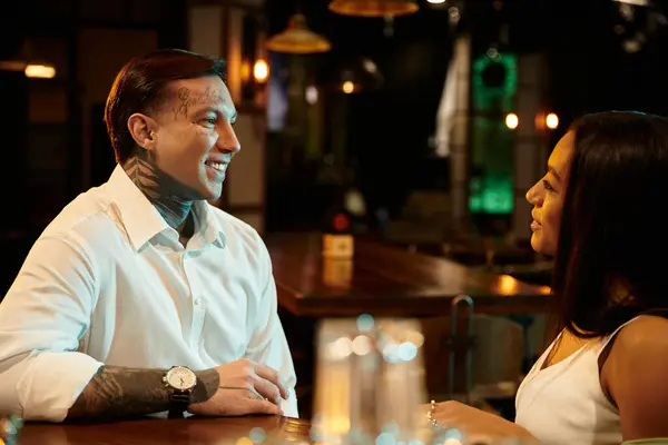 A young couple shares smiles and connection over drinks on a night out at a vibrant bar. — Stock Photo