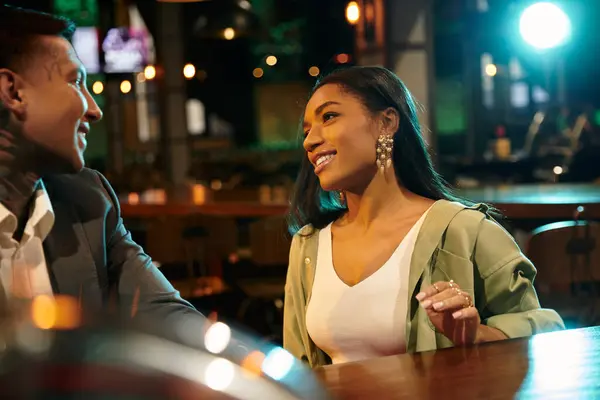 A vibrant young couple enjoying their evening out, exchanging smiles and laughter at a bar. — Stock Photo