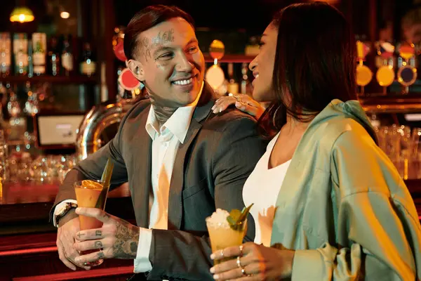 A young couple enjoys cocktails and each others company at a lively bar. — Stock Photo