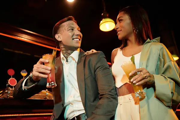 Tattooed couple shares laughter and drinks during a lively night out at the bar. — Stock Photo