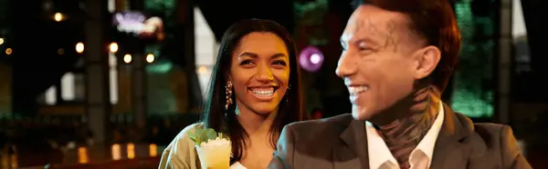 A vibrant multicultural couple shares joyful moments on a night out in a lively bar. — Stock Photo