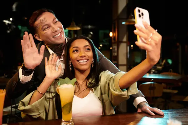 Young couple smiles and takes a selfie during a lively night at a bar. — Stock Photo