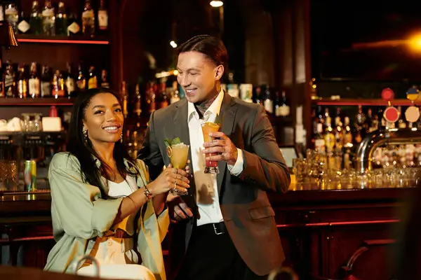 A young multicultural couple enjoys cocktails while laughing and having a fun night out. — Stock Photo