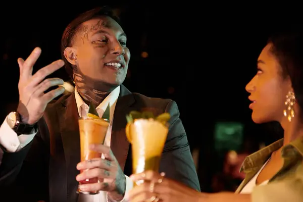 Young multicultural couple shares laughter and drinks on a lively evening date. — Stock Photo